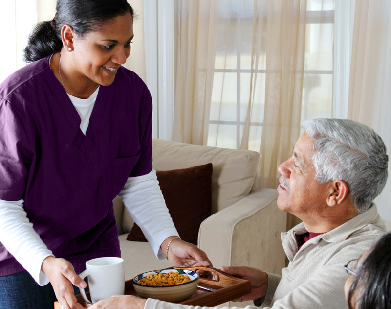 Image of Rothleys home care worker serving a man with his dinner on a tray